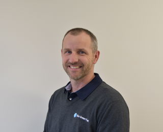 Mann med kort hår smiler til kameraet 